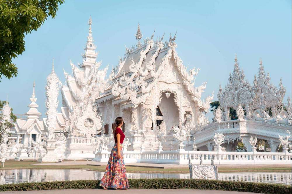 Un touriste prend une photo avec Wat Rong Khun à Chiang Rai